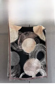Close-up of abstract circular print and soft fringe trim on thick cashmere-like scarf