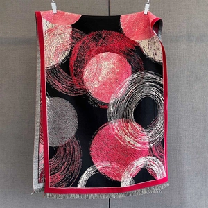 Close-up of thick winter shawl fabric featuring red dots, spiral patterns, and fringe