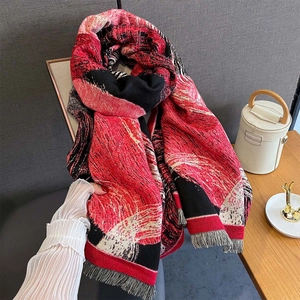 Detailed view of thick red and black geometric pattern knit shawl with fringe trim