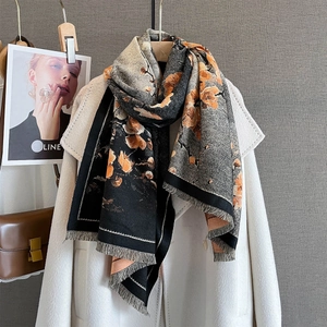 Détail de l'écharpe à fleurs avec franges sur un manteau blanc en laine