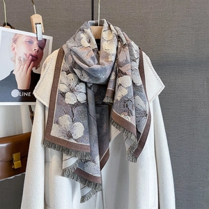 Détail d'une écharpe fleurie en cachemire à franges portée sur un manteau blanc
