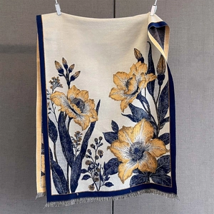 Gros plan d'une écharpe en jacquard avec fleurs dorées et bordures à franges