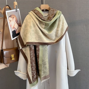 Detail of paisley floral scarf with tassels draped over a white wool coat