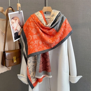 Detail of color-block scarf with paisley print and fringe, styled on a wool coat