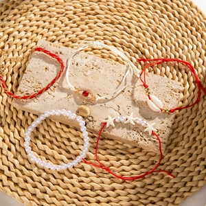 Close-up of bohemian summer bracelet set with seashell and evil eye charms on stones