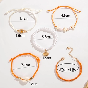 Detail shot of beach style bracelet set with starfish, evil eye and pearls on white base