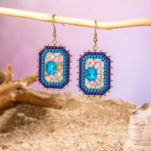 Detailed view of vintage boho tassel earrings with blue crystals on a natural branch