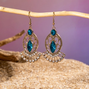 Detail of vintage bronze bohemian earrings with blue gems and intricate hollow carvings