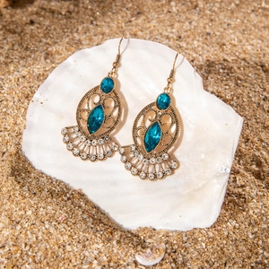 Bohemian retro drop earrings with blue stones on white shell and golden sand background