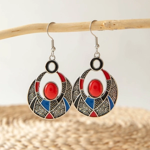 Detail of vintage bohemian earrings with red resin gems hanging on a branch