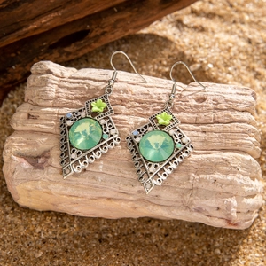 Detail of vintage bohemian earrings with green crystals on a rustic wood background