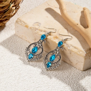 Detailed close-up of Bohemian silver earrings with sky blue teardrop stones on stone