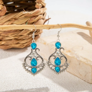 Close-up of bohemian hollow earrings with blue teardrop crystals on natural branches