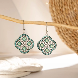 Detailed view of silver bohemian drop earrings with green stones on a wooden branch