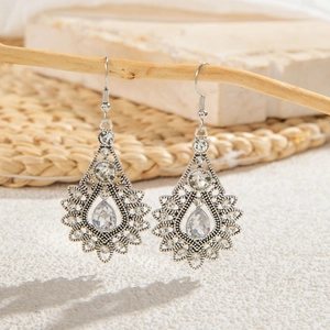 Macro detail of vintage hollow teardrop earrings with crystals and silver finish