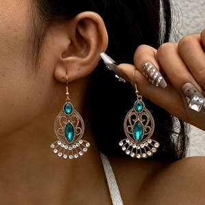 Vintage gold hollow earrings with blue gems and rhinestones on model's ear