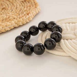 Macro detail of glossy 12mm black round beads on an ethnic style beaded bracelet
