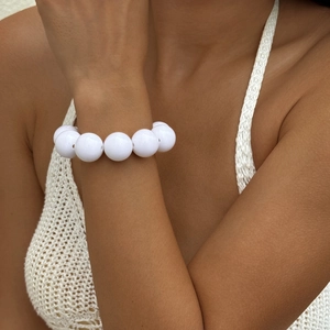Ethnic style bracelet with large white round beads worn by a model in a minimal setting