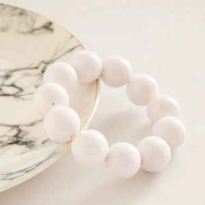 Detail of white glossy oversized resin beads on a minimalist ethnic beaded bracelet