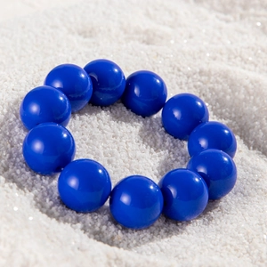 Macro detail of glossy blue oversized round beads on a beaded ethnic style bracelet