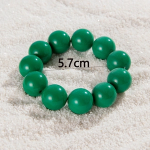 Detail shot of green beaded bracelet with 5.7cm inner diameter on white sand background