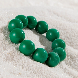 Detailed close-up of vibrant green beads on white crystalline sand background