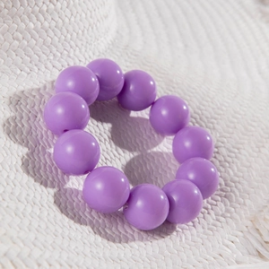 Detail of large purple beads on a woven texture showing polished round resin finish