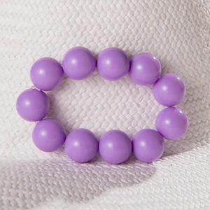 Macro view of glossy purple resin beaded bracelet on a white textured straw background
