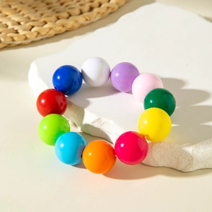 Close-up of colorful acrylic beaded bracelet on white textured stone display stand