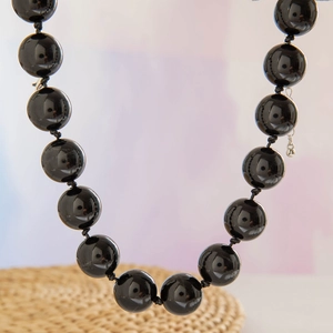 Detail of 10mm black bead necklace with polished finish and secure knotting craft