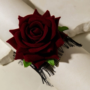 Detail of gothic dark red velvet rose with green leaves and black lace on stone base