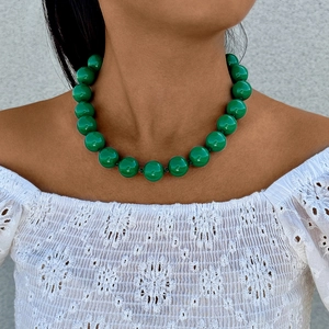 Detail of bohemian green round bead necklace with polished finish on model in white lace
