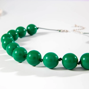 Macro shot of glossy green beads and silver extension chain on a bohemian necklace