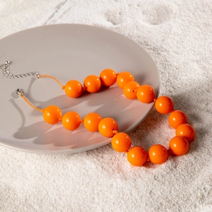 Detail of vibrant orange beaded necklace with silver lobster clasp and extension chain