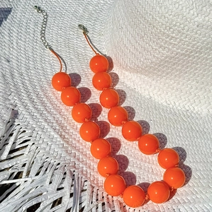 Detail of bohemian orange bead necklace on straw hat showing lobster clasp and chain