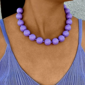 Close-up of bohemian purple beaded necklace worn by a model with knit top