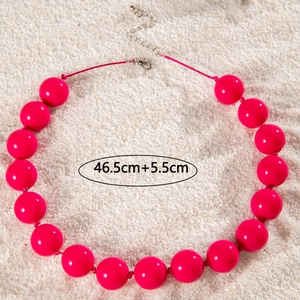 Detail of rose red beaded necklace with lobster clasp and extension chain on white sand