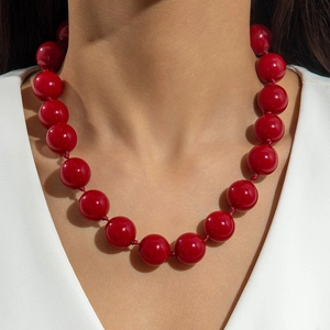Detailed view of large glossy red round resin beads on a bohemian style necklace