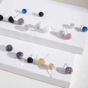 Dettaglio di orecchini a sfera con strass colorati pavé su supporto bianco elegante