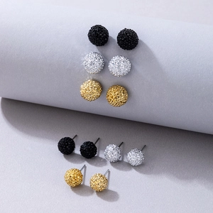 Dettaglio di tre paia di orecchini a lobo con sfere scintillanti in nero, argento e oro