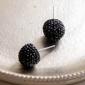 Macro di orecchini a bottone con sfere di cristallo nero su vassoio in metallo champagne