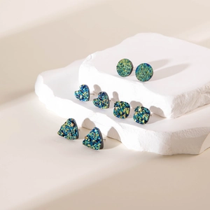 Dettaglio ravvicinato di orecchini geometrici in druzy colorati su base di pietra bianca