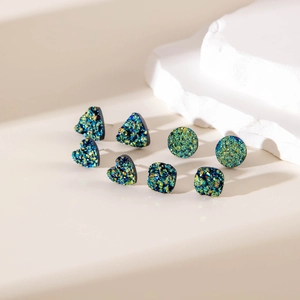 Dettaglio di orecchini a lobo geometrici druzy colorati in forme di triangolo, cuore e cerchio