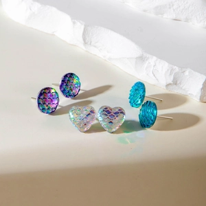 Dettaglio macro di orecchini a scaglia di sirena con finitura iridescente multicolore