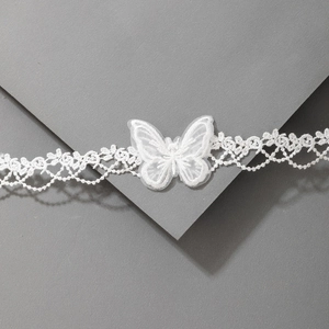 Gros plan d'un tour de cou en dentelle blanche avec papillon 3D et détails délicats
