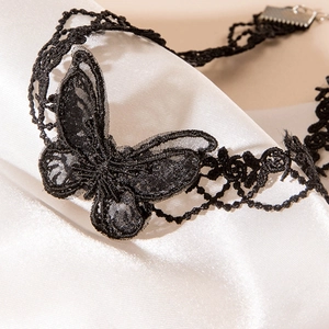 Détails de broderie d'un ras-du-cou papillon en dentelle noire sur tissu de satin blanc