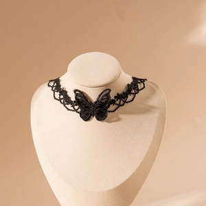 Gros plan du collier choker papillon en dentelle noire avec broderie sur support beige