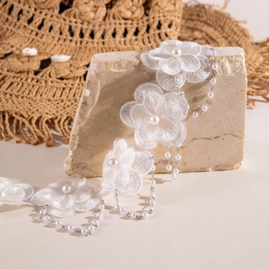 Détail macro du ras-du-cou en dentelle blanche avec perles et fines chaînes en argent
