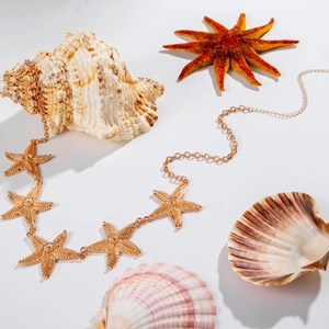 Close-up of golden starfish chain with detailed texture on white sea-themed backdrop
