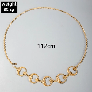 Detail of gold metal waist chain with celestial moon and sun star pendants on grey background
